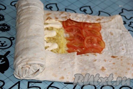 Завернуть края лаваша с двух сторон (как на фото), затем свернуть лаваш с начинкой в плотный рулет.
