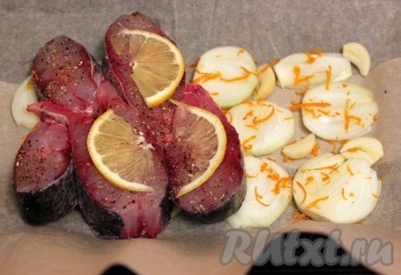 На противень положить пергамент (бумагу для запекания), смазывать её не надо, на бумагу первым слоем выложить кружочки лука, дольки чеснока и цедру лимона (или апельсина), вторым слоем положить кусочки толстолобика и сверху дольки лимона.
