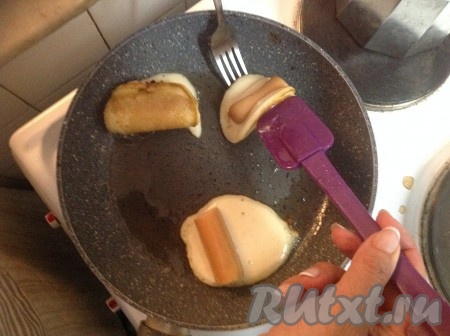 Теперь аккуратно с помощью лопатки и вилки (как на фото) сложить кружок теста пополам, придавая ему форму красивого конвертика (благодаря складыванию оладушка пополам с помощью лопатки и вилки, вытечет меньше теста).