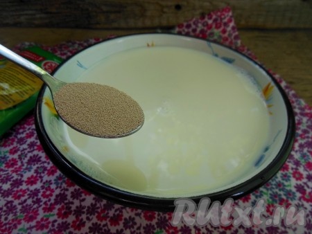 В теплое молоко добавьте щепотку сахара и сухие дрожжи, перемешайте получившуюся опару столовой ложкой и накройте полотенцем.
