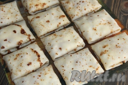 Блины, фаршированные сыром и курицей, выложить в жаропрочную форму.
