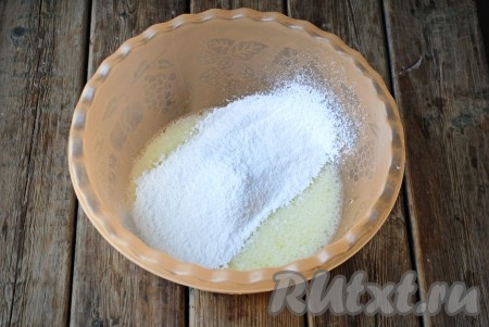 Всыпать частями просеянную муку. После каждой порции добавленной муки тесто нужно хорошо перемешивать ложкой. Когда масса станет плотной и тяжело будет мешать, нужно выложить тесто на стол и продолжить замес руками.
