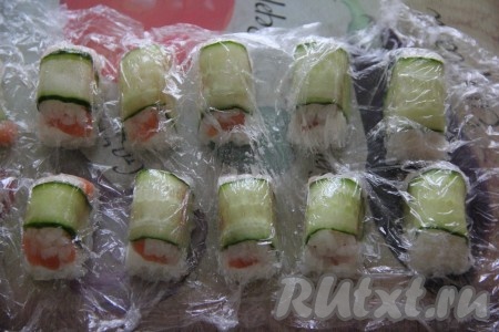 Перевернуть форму с роллами на плоское блюдо и, аккуратно потянув за плёнку, снять форму для льда.
