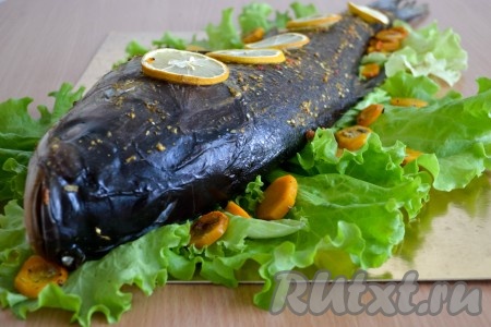 Рыба достаточно крупная, поэтому, чтобы она пропеклась, ее нужно запекать долго, но при низкой температуре. Поэтому духовку выставить на 160-180 градусов и запекать 60-70 минут. Если, приоткрыв дверцу духовки, вы увидите, что на противне вообще нет жидкости и подушка из кружочков моркови начинает подгорать, то влейте немного горячей воды на противень.
