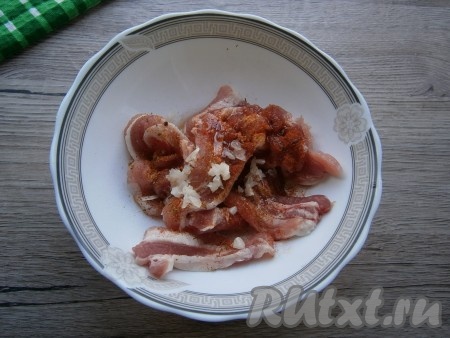 Каждую пластину бекона разрезать на 3 части, добавить специи для мяса, немного соли, паприку, растительное масло и пропущенный через пресс чеснок, перемешать и оставить на 30 минут.
