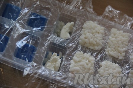 Хорошо промыть рис проточной водой. Выложить промытый рис в кастрюлю и залить водой в соотношении 1 к 2 (то есть воды должно быть в 2 раза больше, чем риса), поставить на огонь. Когда вода закипит, уменьшить огонь, прикрыть кастрюлю крышкой и варить рис, примерно, 15-20 минут&nbsp;на среднем огне (вода должна полностью выпариться). В готовый рис можно добавить рисовый уксус, перемешать, накрыть полотенцем и дать полностью остыть. Рис можно сварить заранее и хорошо остудить. Форму для льда застелить пищевой плёнкой. На дно каждой лунки в форме для льда выложить немного риса. Поверх риса разместить немного творожного сыра.