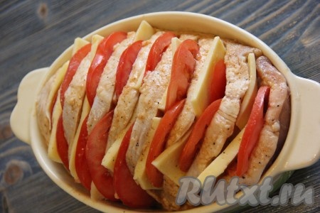 Свинину достать из пакета и выложить в жаропрочную форму (при желании, форму можно смазать маслом). В прорези между кусочками мяса выложить сыр и кружочки помидора (как на фото).
