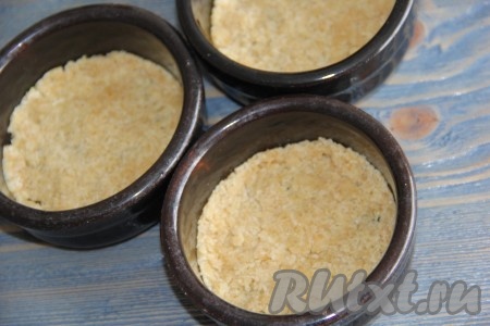 На дно керамических формочек выложить немного крошки и слегка её утрамбовать.