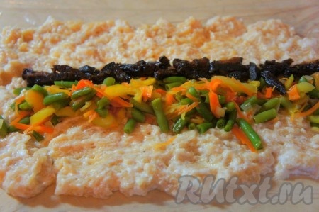 Расстелить пищевую плёнку, на неё выложить куриный фарш, смешанный с белками. Фарш распределить по плёнке, чтобы получился небольшой прямоугольник. В центр пласта из фарша выложить остывшие овощи в виде полоски (как на фото), рядом можно выложить полоску из нарезанного чернослива.
