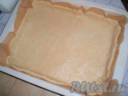 Затем тесто раскатать в пласт между двумя листами пергамента, перенести прямо с бумагой в форму для выпечки и сформировать основу с бортиками.
