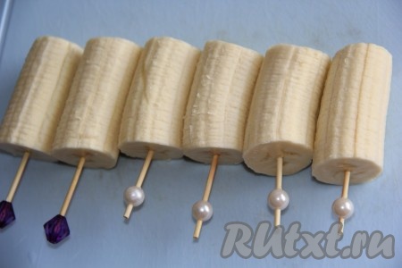 Очистить бананы и нарезать на кусочки длиной, примерно, 10 см. Вставить в серединку каждого кусочка банана, по всей длине, палочку или декоративную шпажку. Положить бананы в морозилку на 30 минут.
