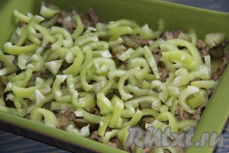 Болгарский перец вымыть, удалить семена и нарезать на полукольца. Выложить перец на мясо.
