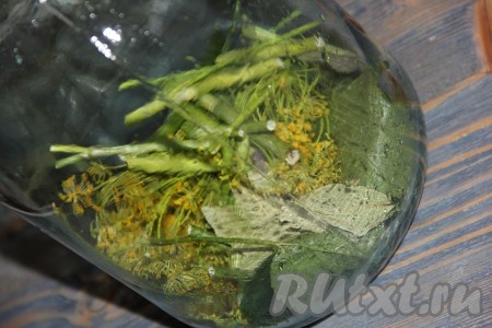 В простерилизованную банку выложить листья смородины, дуба, вишни, хрена, зонтики укропа, перец горошком и лавровые листья. Чеснок очистить и добавить в банку.
