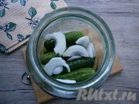 Огурцы вымыть и разместить их в банке. Сверху выложить еще одну часть нарезанного лука.
