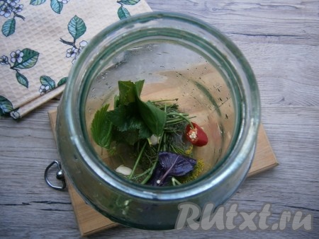 На дно чистой банки выложить укроп, очищенный чеснок, горький перец, листья смородины и листочек базилика.
