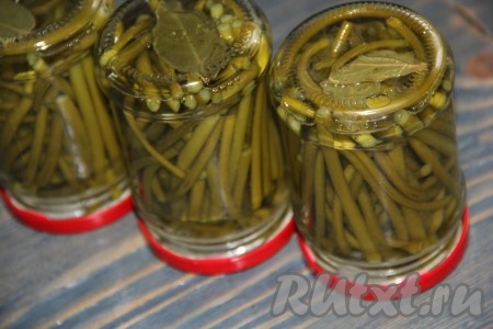 Достать баночки с маринованными чесночными стрелками из кастрюли, закрутить крышки. Банки, перевернув вверх дном, укутать в одеяло и оставить до полного остывания.