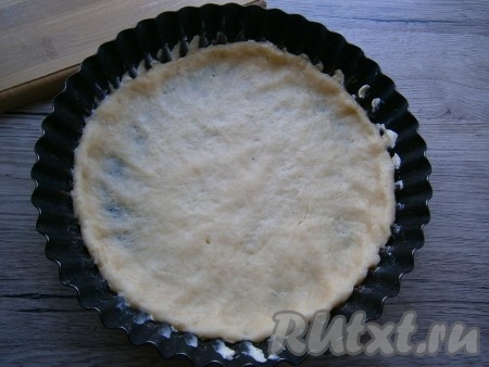 Одну треть теста отложить в сторону, остальное тесто растянуть руками по дну формы диаметром 18-20 см, формируя небольшие бортики (форму, при желании, перед выкладыванием теста можно смазать маслом).
