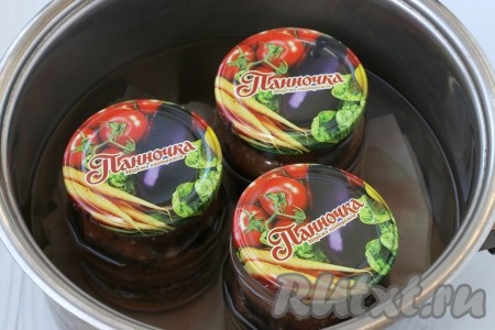 После того как все банки будут заполнены баклажанами, заготовку нужно стерилизовать. Для этого нужно застелить дно кастрюли тканью, поставить банки и залить в кастрюлю тёплую воду по "плечики" банок. Крышки ошпарить кипятком, накрыть ими банки. Кастрюлю с банками поставить на огонь и с момента закипания воды стерилизовать 10 минут на среднем огне.
