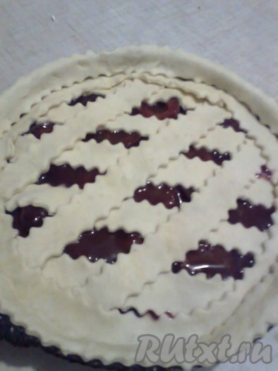 Раскатать меньшую часть песочного теста, фигурным ножом нарезать его на полоски, выложить их в виде решётки на поверхность сливового пирога.