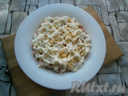 Следующим слоем выложить нарезанные кубиками, предварительно отваренные, охлажденные и очищенные яйца, сверху нанести сеточку из майонеза и немного посолить.
