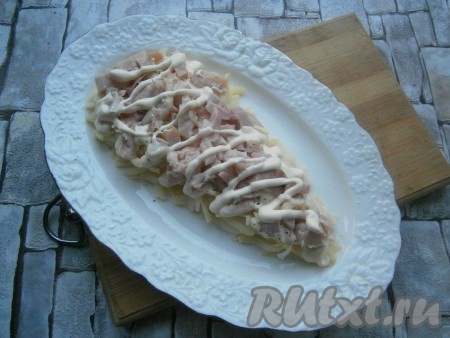 Курицу нарезать небольшими кусочками и выложить ее вторым слоем, нанести сеточку из майонеза.
