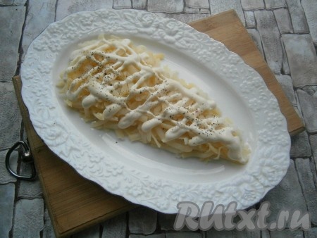 На овальную или прямоугольную тарелку выложить очищенный и натертый на крупной или средней терке картофель в виде грозди винограда. Слой картофеля немного посолить и поперчить, нанести сеточку из майонеза.