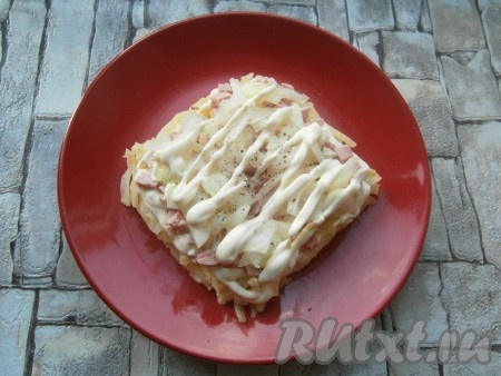 Промариновавшийся лук отжать и выложить его на колбасу, поперчить, смазать майонезом.
