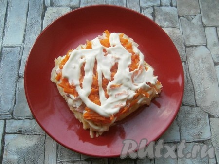 Следующим слоем выложить натертую на средней терке оставшуюся морковь, хорошо смазать майонезом.
