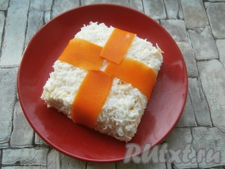 Весь салат аккуратно покрыть натертыми на мелкой терке белками. Слайсы моркови обсушить и украсить ими салат в виде ленты (крест-накрест) (как на фото).
