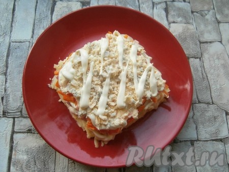 Яйца разделить на желтки и белки. Желтки натереть на средней терке и выложить следующим слоем, нанести сеточку из майонеза.
