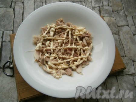 На тарелку выложить 2/3 части отварной курицы, порванной руками на волокна, нанести сеточку из майонеза, немного поперчить.
