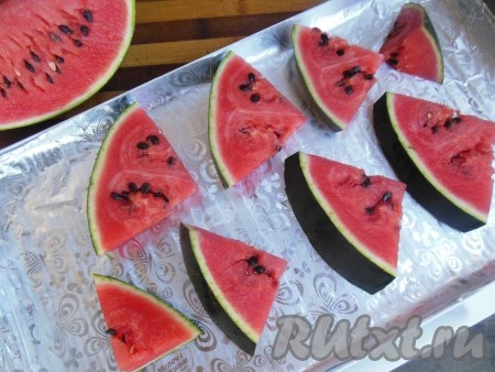 Поднос застелите фольгой, разложите дольки арбуза, чтобы они не соприкасались друг с другом (так мы избежим слипания долек арбуза во время заморозки).
