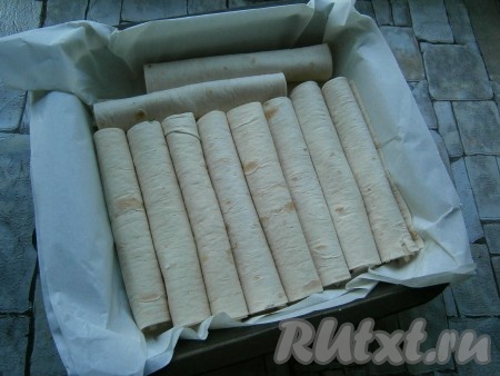 Лаваш с картофельным пюре свернуть трубочкой. Таким же образом сформировать все трубочки и выложить их плотно друг к другу в форму для запекания или на противень в один ряд. Форму можно застелить пергаментом, можно и не делать этого.