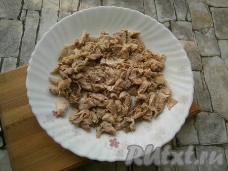 Мясо курицы предварительно отварить в подсоленной воде в течение 40-45 минут, остудить. Порвать мясо на волокна и выложить первым слоем на тарелку, немного его поперчить.