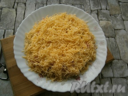 Последним слоем выложить натертый на средней терке твердый сыр. Сыром покрыть и бока салата. Майонезом не смазывать.
