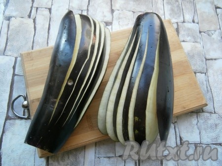 В каждом баклажане сделать по 5 разрезов вдоль, но не до конца, начиная разрезы с противоположной к хвостовой части стороны баклажанов (как на фото).
