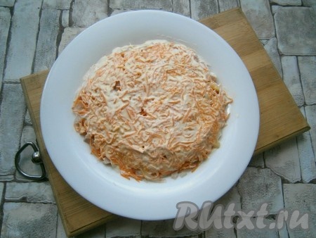 Далее идёт слой очищенной и натертой на средней или мелкой терке сырой моркови. Морковь немного посолить и хорошо смазать майонезом.
