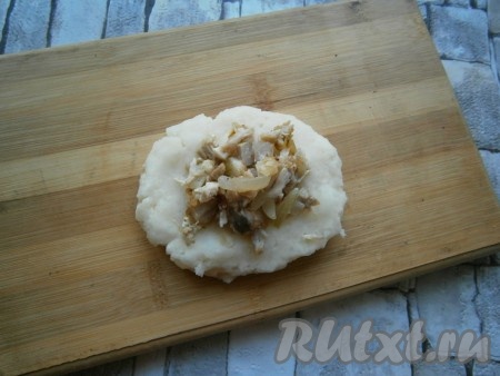 Чуть влажными руками из небольшой части картофельной массы слепить лепешку среднего размера, в центр выложить 1 столовую ложку остывшей куриной начинки.
