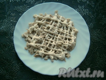 На небольшую тарелку первым слоем выложить охлажденное и нарезанное отварное куриное мясо (можно использовать грудку или мясо с ножек и бедрышек, предварительно отварив около 40-45 минут в подсоленной кипящей воде). Мясо чуть поперчить, нанести сеточку из майонеза.