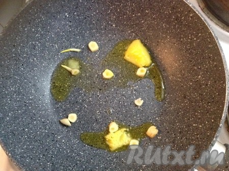 Сковороду ставим на огонь, растапливаем топленое масло и добавляем очищенный чеснок, нарезанный на лепестки.