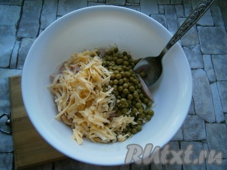 Сюда же добавить натертый на крупной терке сыр и консервированный горошек, предварительно слив с него жидкость.
