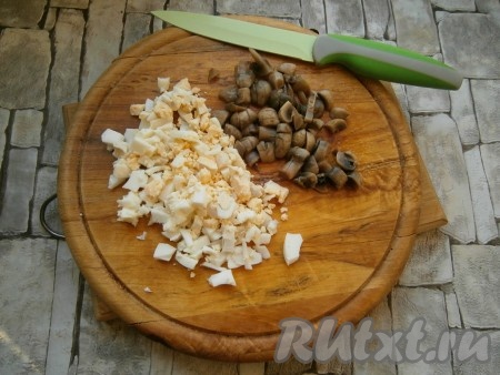 Маринованные шампиньоны нарезать кусочками, яйца порубить.
