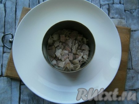 Свинину, отваренную в течение 1-1,5 часов в подсоленной воде, остудить, нарезать на небольшие кусочки. В центр тарелки поставить кулинарное кольцо. Выложить в кольцо нарезанное мясо, оно будет первым слоем салата.