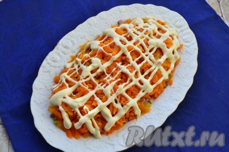 На огурчики разместить очищенную варёную морковь, натёртую на крупной тёрке, немного сверху посолить, нанести сеточку из майонеза.