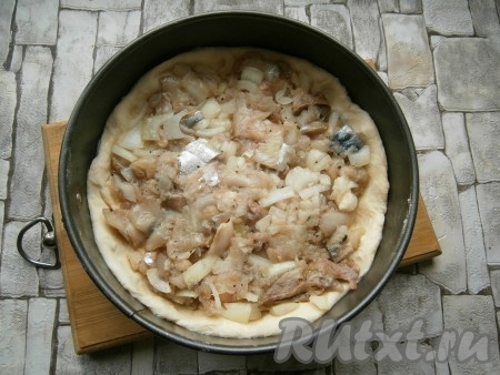 Тесто разделить на 2 неравные части - одну больше, одну чуть меньше. Большую часть теста немного раскатать и выложить в разъемную форму диаметром 17-19 см (при желании, форму перед выкладыванием теста можно смазать маслом), формируя небольшие бортики. Выложить на тесто всю рыбу, разровнять.
