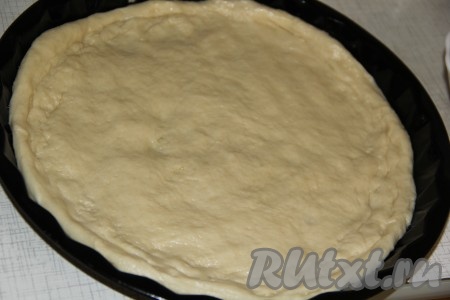 Дрожжевое тесто, замешанное в хлебопечке или вручную, хорошо обмять. На столе, присыпанном мукой, раскатать тесто в круг и выложить в форму для запекания, предварительно смазанную растительным маслом. Сформировать бортик из теста. У меня форма диаметром 26 см.
