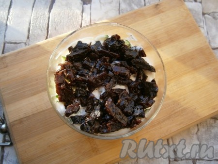 Далее идёт слой нарезанного на кусочки чернослива (если чернослив сухой, тогда предварительно залейте его кипятком минут на 10, а затем обсушите), его тоже нужно разложить по трём стаканчикам, смазать немного соусом из майонеза и сметаны.