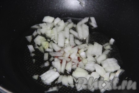 В сковороду вок или сковороду с высокими бортиками влить масло. Лук очистить, мелко нарезать, добавить в сковороду и обжарить на масле, помешивая, до золотистого цвета.

