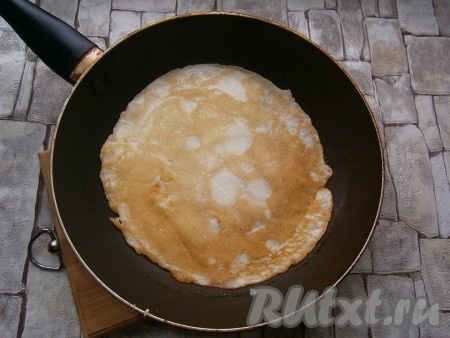 Жарить блинчик до румяности с двух сторон (примерно по 1 минуте с каждой стороны), затем переложить тонкий блин на тарелку. Периодически перемешивая блинное тесто в миске и смазывая сковороду перед выпечкой очередного блина только по мере необходимости, постепенно пожарить все блинчики, складывая их горкой на тарелку.
