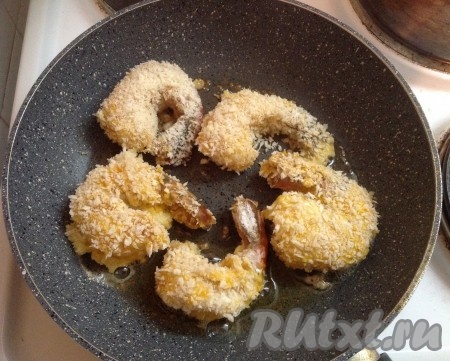 Затем кладём тигровые креветки в кляре на разогретую сковороду с чесночным маслом. Жарим на среднем огне до золотистой корочки с одной стороны.
